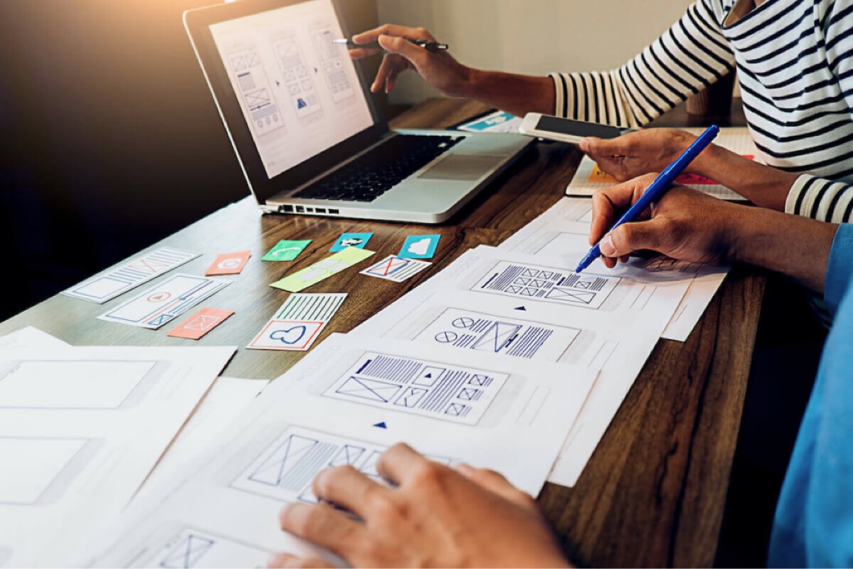 Designers reviewing wireframes and sticky notes at a desk